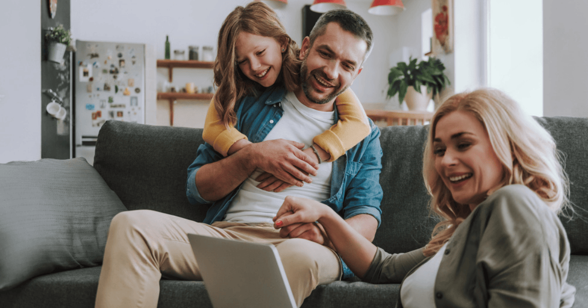 Happy family on a couch looking at a laptop.