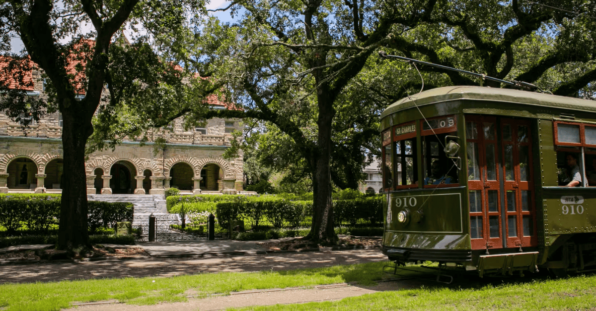 GroupSync | New Orleans for Group Travel | Green trolley car in front of a historic mansion on a tree-lined street