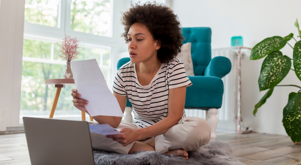 Woman reviewing papers in front of a laptop