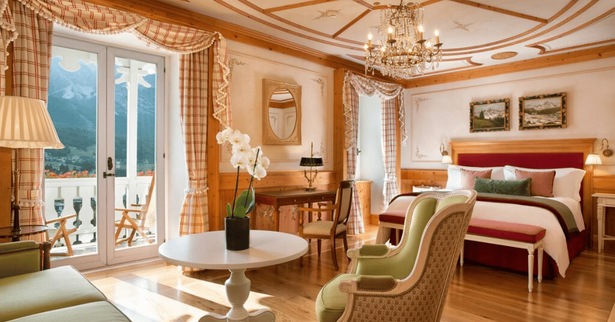 Large hotel room with chandelier and balcony overlooking the mountains