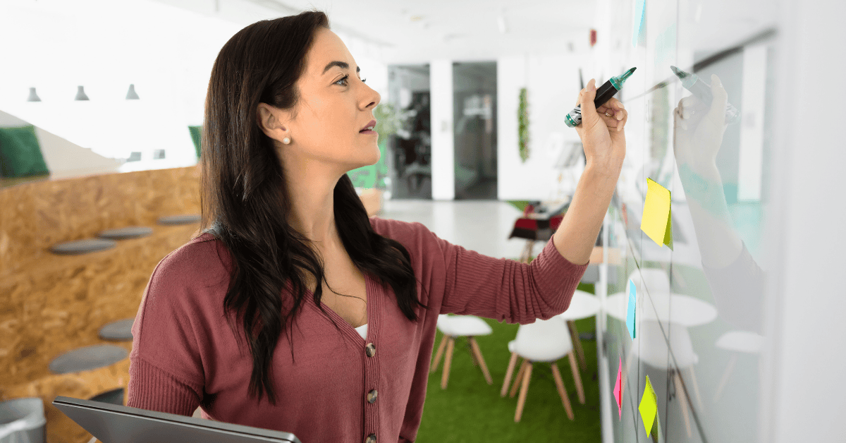 Professional woman writing on a whiteboard in a casual office setting