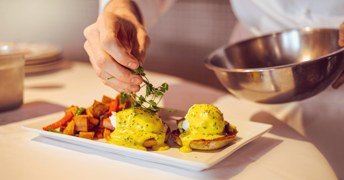Chef garnishing eggs benedict
